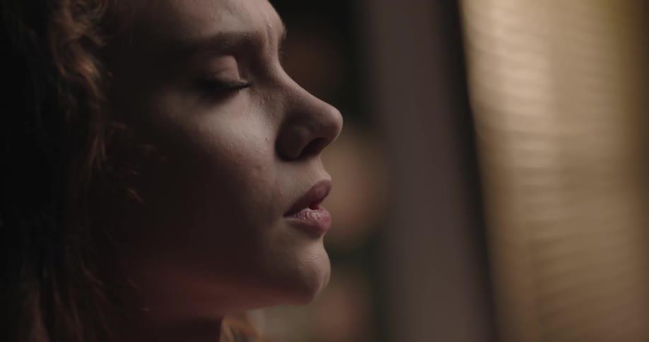 A woman is standing by a window in her home