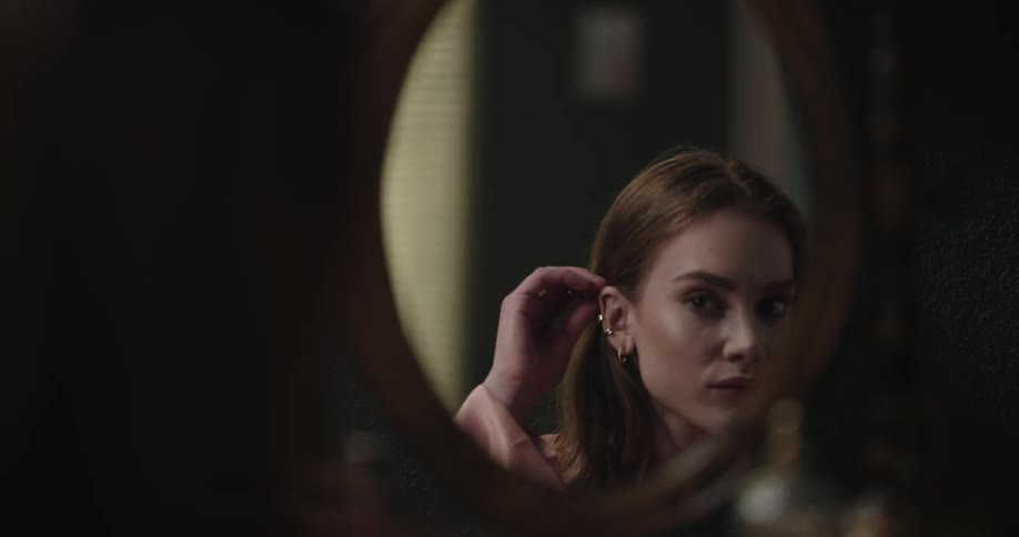 A woman is looking at her reflection in the mirror