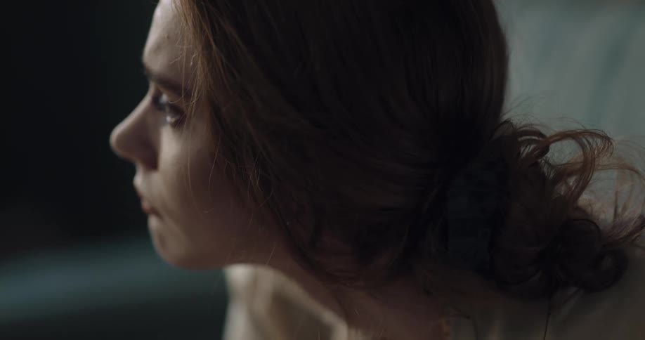 A woman is sitting on a sofa and looks worried