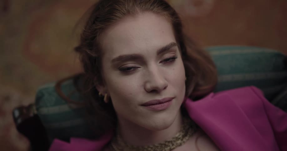 A woman is smiling and laying down on a couch