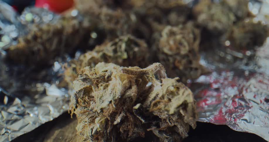 Dried marijuana buds lay on foil on a table