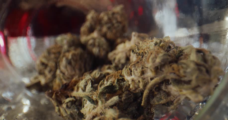 Dried marijuana clusters sit in glass container