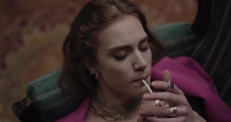 Young beautiful and well dressed woman lying on the couch smoking a cigarette