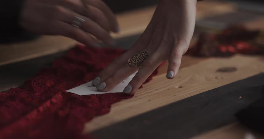 Female tailor drawing a pattern over a piece of red fabric