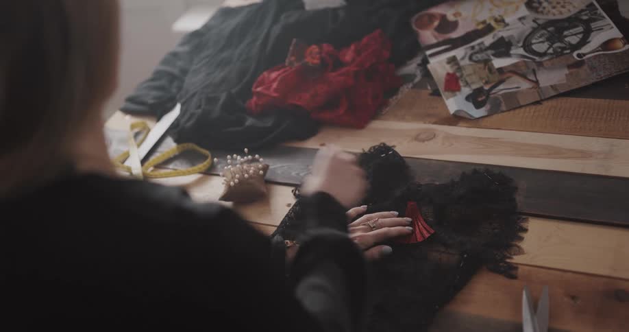 A woman pins together pieces of lace for sewing
