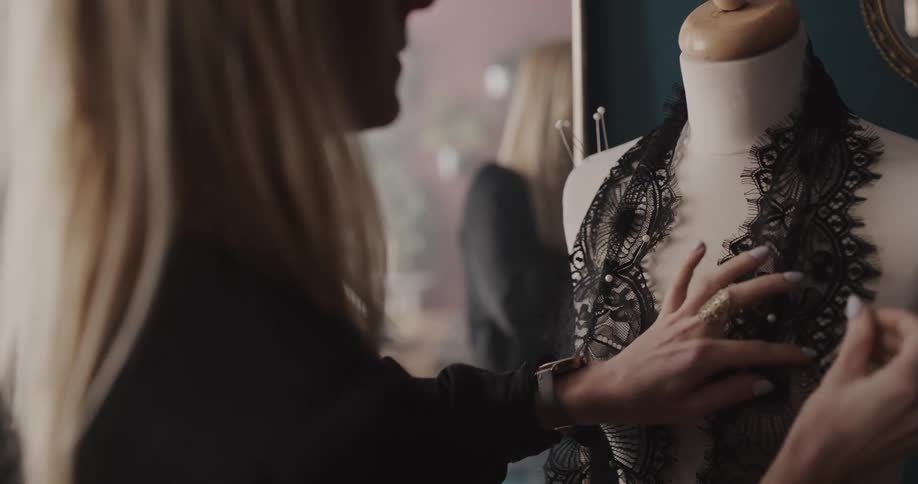 A fashion designer pins fabric to a mannequin while constructing a garment