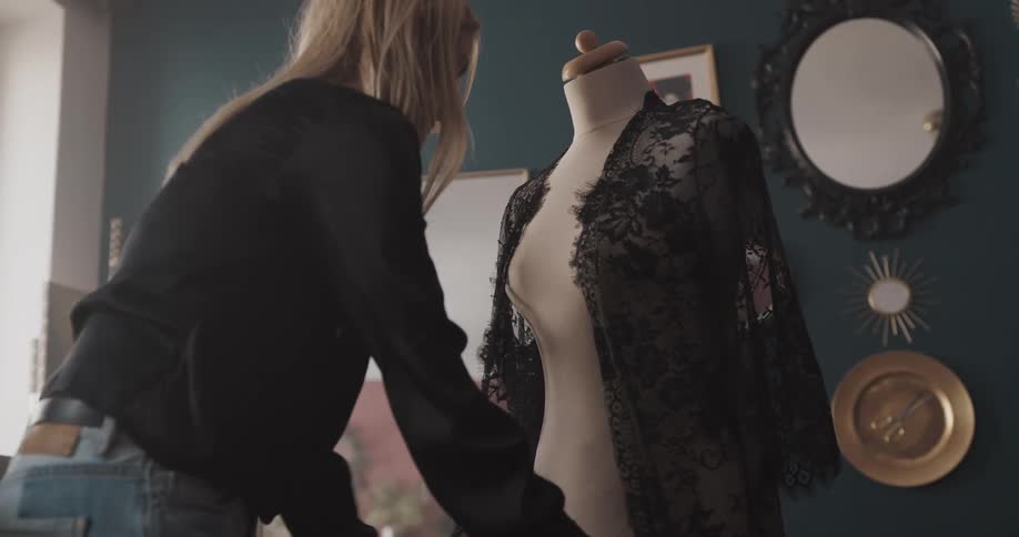 A woman dresses a mannequin in a sheer robe