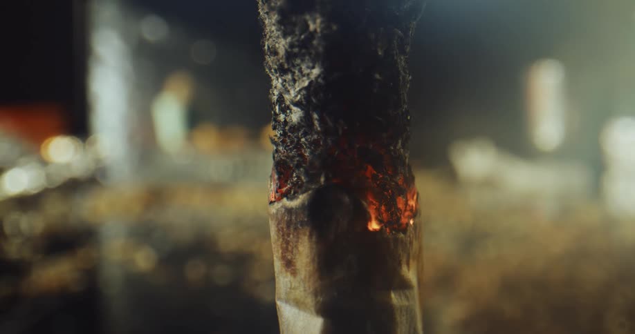 Close up of white smoke coming out of an erect cigarette burning fast