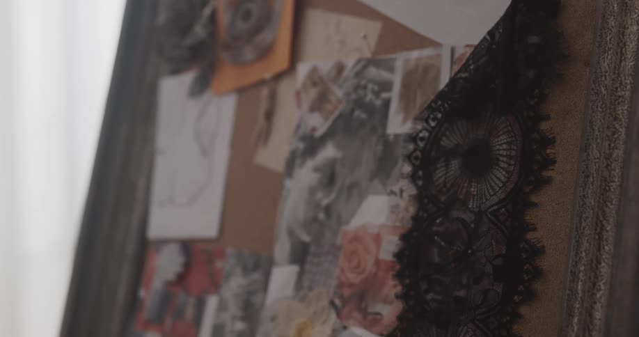 Woman pins lace onto cork board being used as a design board