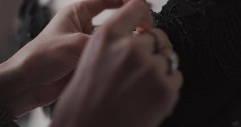 A woman is sewing pieces of clothing together