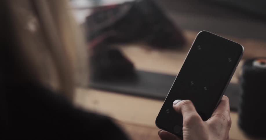Blonde womans hand tapping on a smartphone screen indoors
