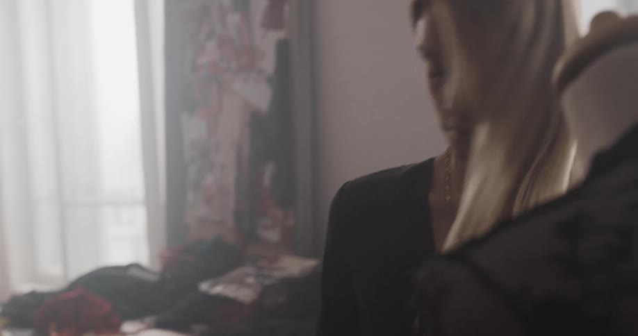 A woman is creating an article of clothing in her shop