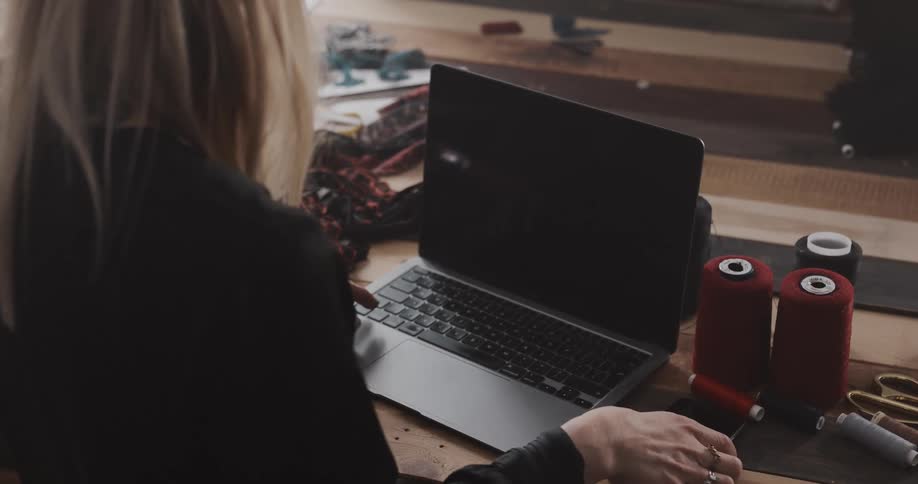 A woman is talking on her cellphone and typing on a laptop