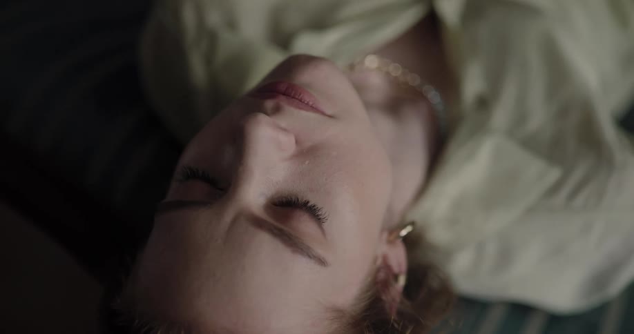 Young woman sitting on the couch with her head tilted back opening her eyes