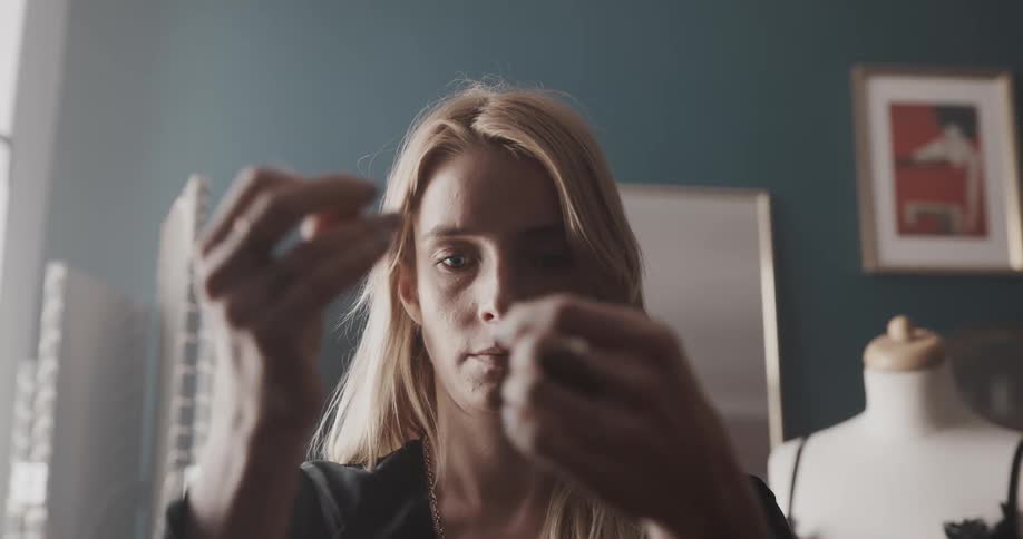 A woman puts thread through the eye of a needle