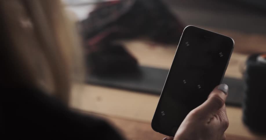 A woman is holding her cellphone and sitting indoors