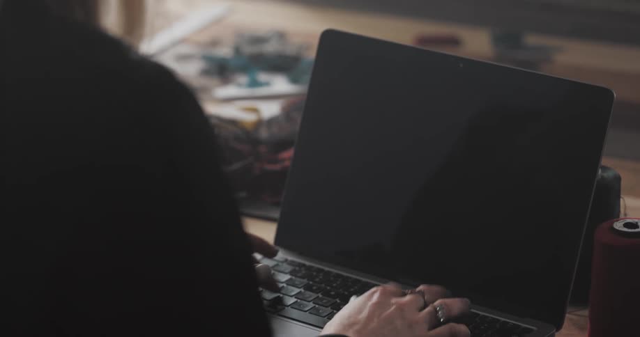A woman is typing on a laptop while sitting indoors