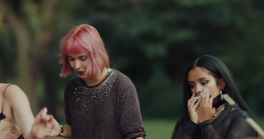 Group of young happy female friends dancing and playing musical instruments in a public park during daylight
