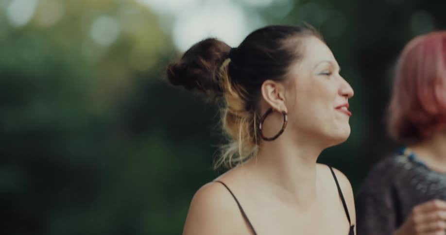 Two young female friends dancing and having fun together in a public park during daylight