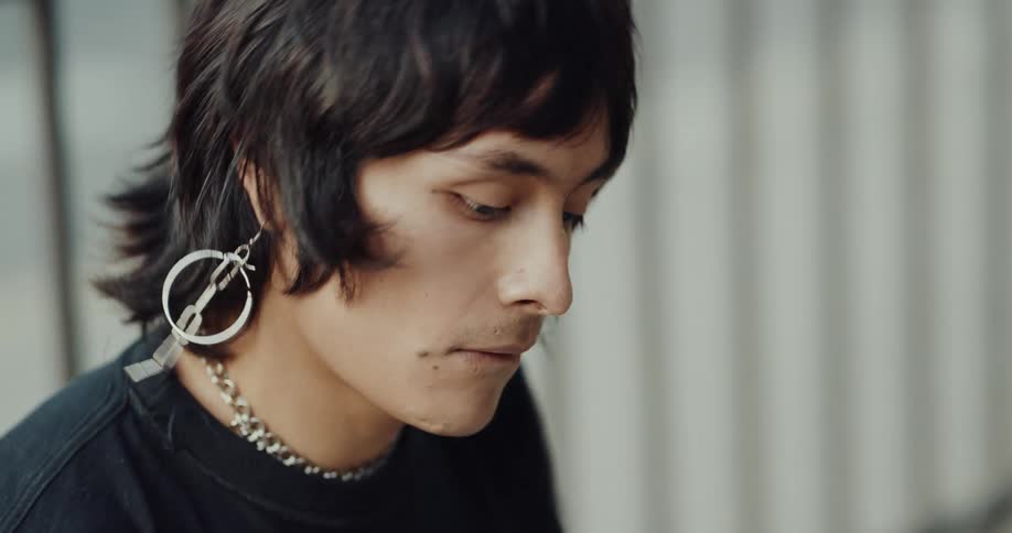 Stylish young man wearing an earring dancing to music and smiling