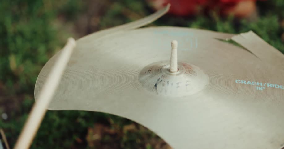 A person playing music on a broken drum set outdoors