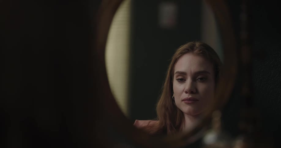 A woman is looking at her reflection in a mirror