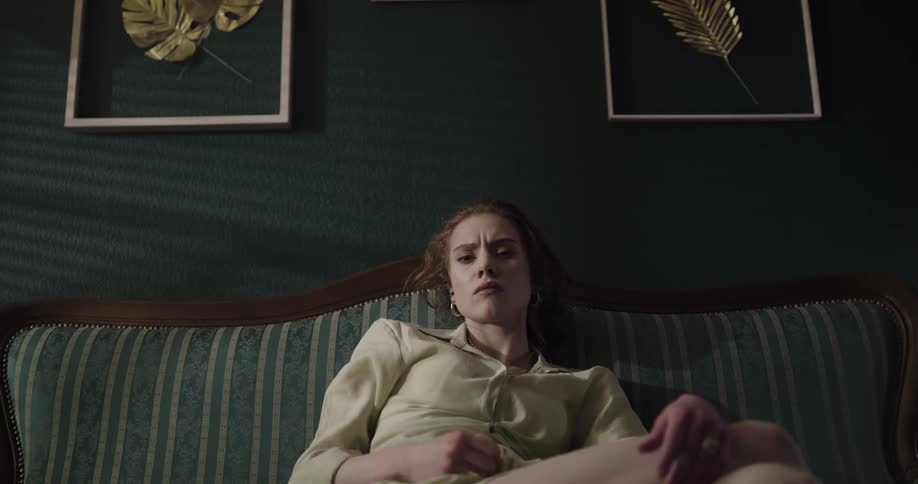 A woman is sitting on a couch in her room