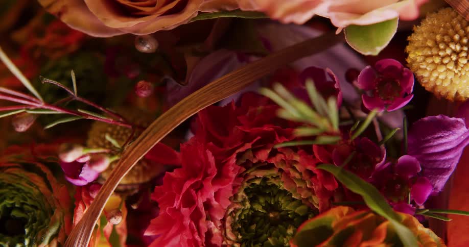 Vivid multicolored floral arrangement in basket sits on wood surface