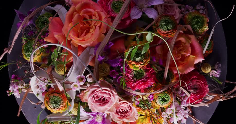 Colorful flower arrangement composed of pink purpleyellow and orange flowers sits on purple table