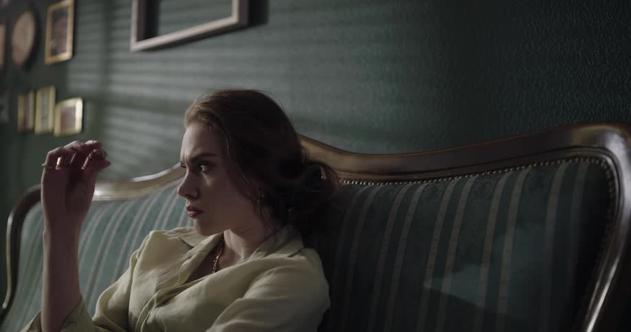 A woman is sitting and resting on a sofa