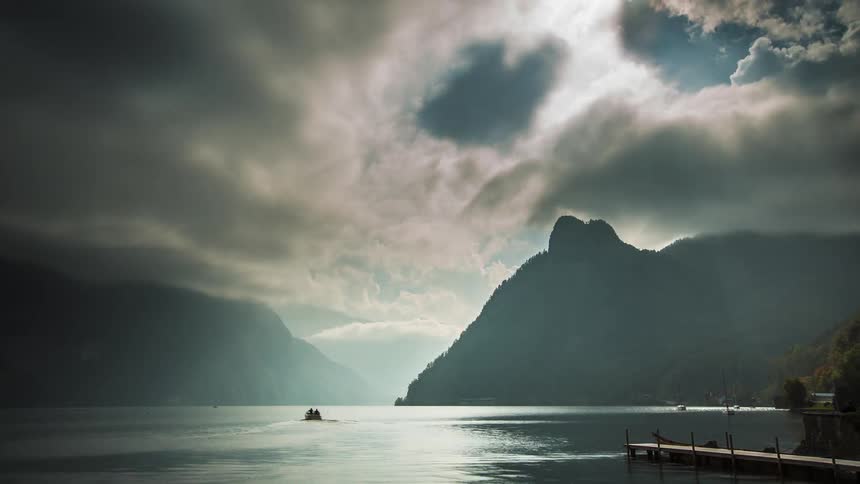 People ride in boats on a mountain river and the clouds from above reflect on the water as they move across the sky