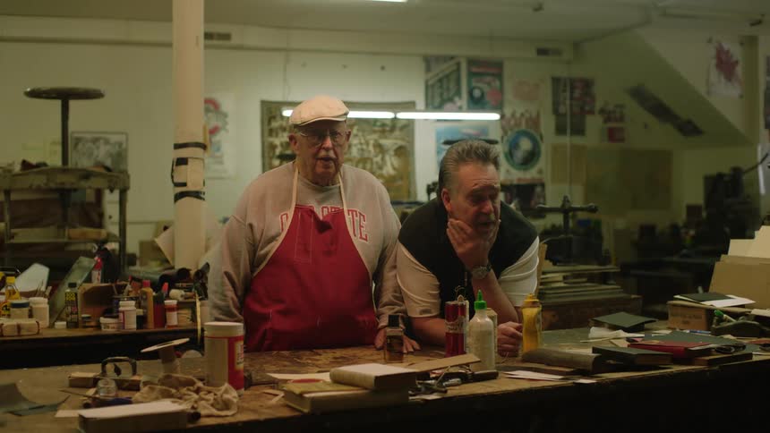 Two men pose together in workshop