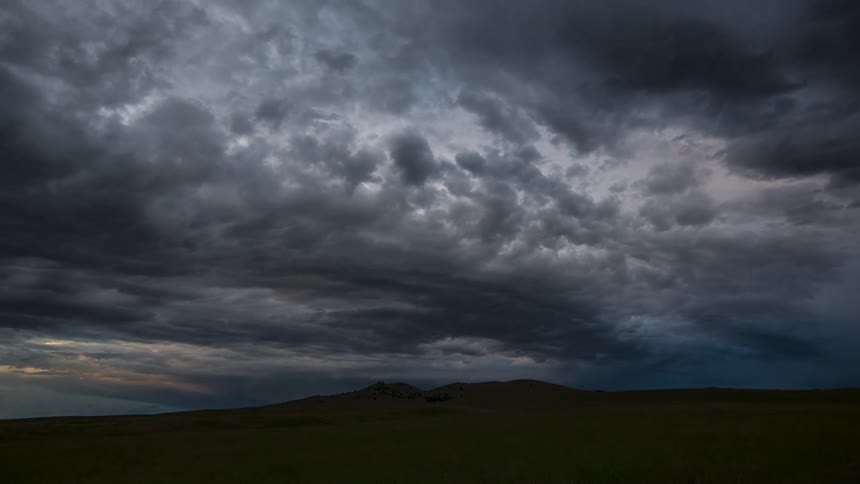 Clouds move over rural country land as the sky gets darker and becomes night