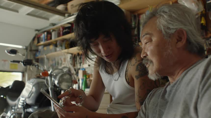 Father and son looking at photographs in the garage at home