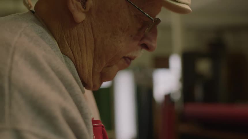 Elderly man wearing apron concentrates on his work