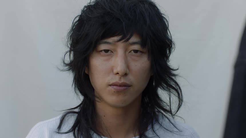 A young asian man stares at the camera