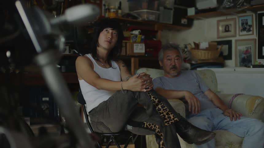 Two asian men sitting on the couch in the living room watching television