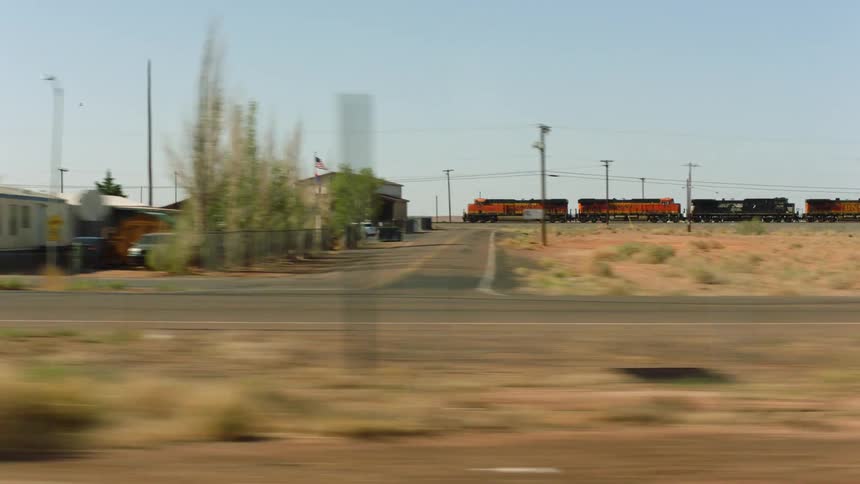 A train travels behind neighborhood buildings under a clear sky