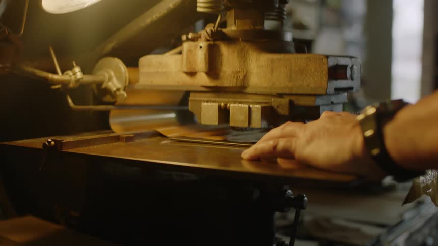 Man uses a machine to stamp film in a workshop