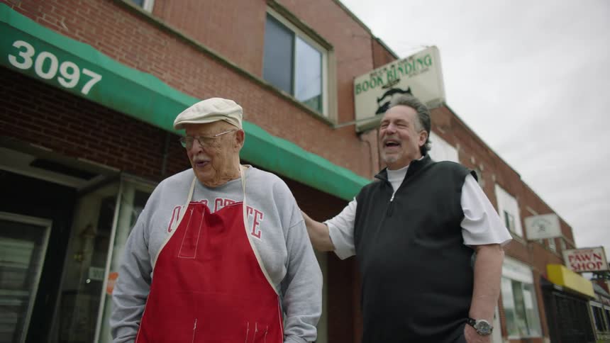 Father and son laugh while standing in front of a small town shop
