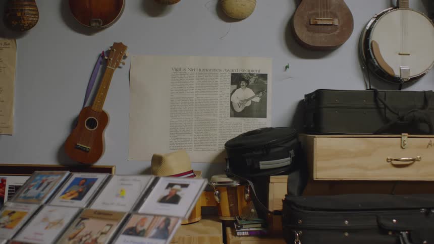String instruments hang on the wall near table holding instrument cases and audio cds