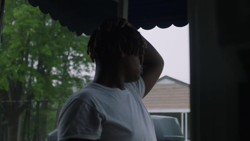 Man stands under awning of house with truck parked nearby