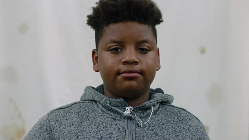 Black teenage boy wearing a gray hoodie with a neutral facial expression