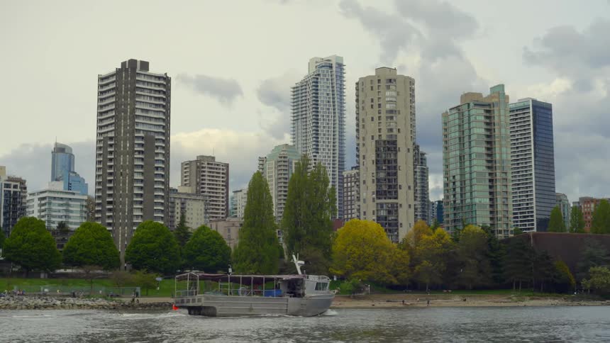People walking and hanging out on the beach and park when a boat tour travels past
