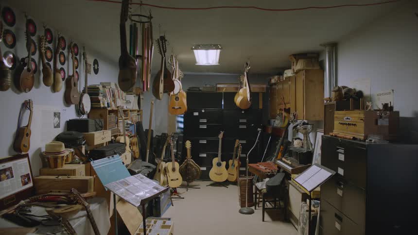 Room full of guitars and other plucked string instruments hanging from the ceiling