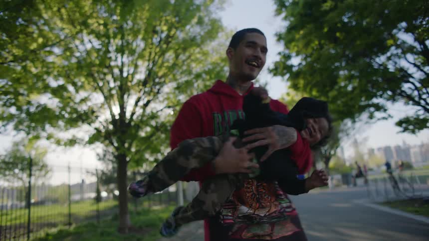 Father spins around with his infant son in a park in the morning