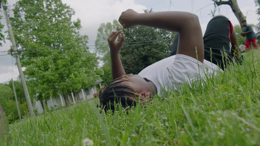 Two young men resting in the green grass on a park