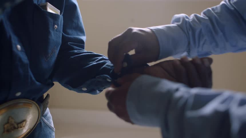 Son helps father to button up the sleeve of a shirt