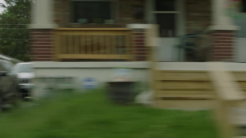City neighborhood homes with cars parked in driveways big front porches and small lawns
