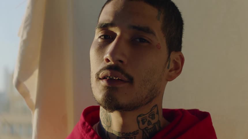 A man has gold teeth and tattoos
